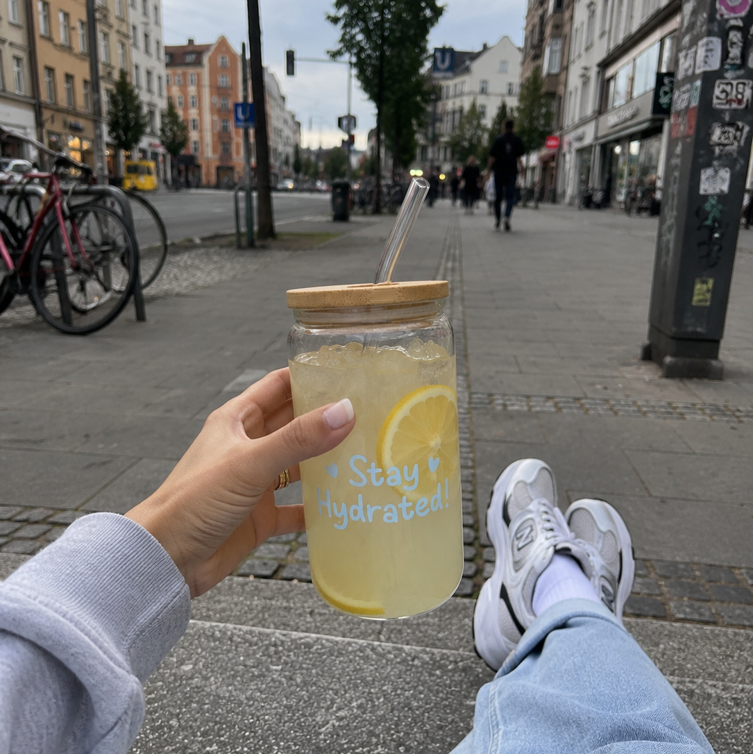 Stay Hydrated Trinkglas mit Zitronenwasser, Bambusdeckel und Glasstrohhalm auf hellem Hintergrund